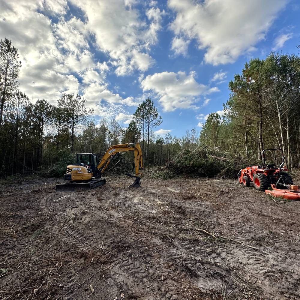 Excavator and brush cutter on a freshly cleared lot