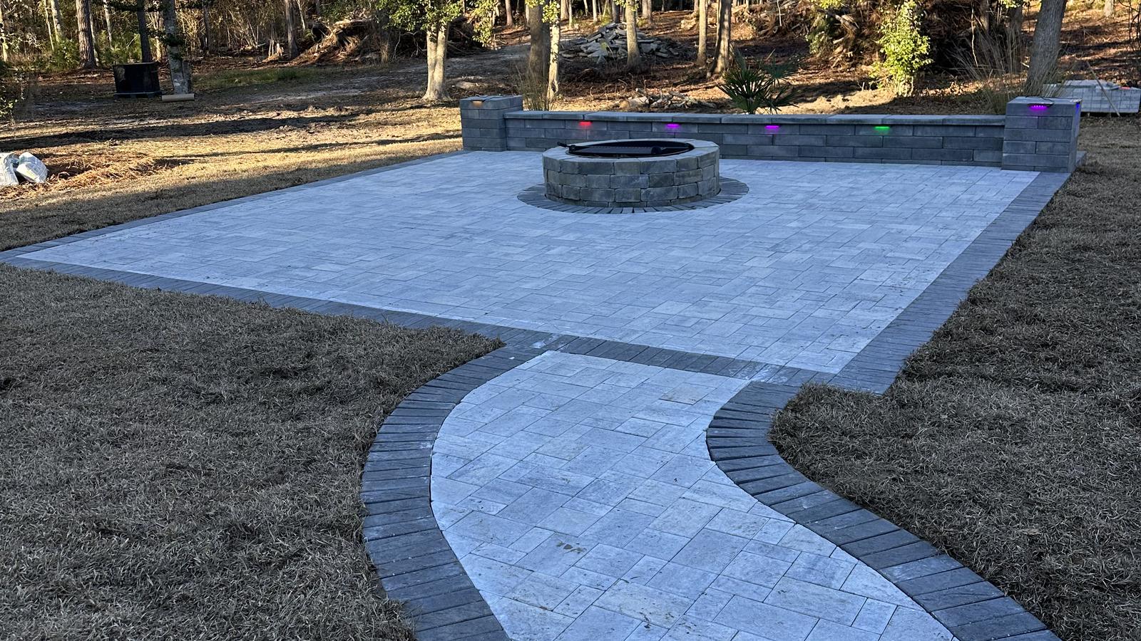 Finished paver patio with fire pit and curved walkway in late afternoon light